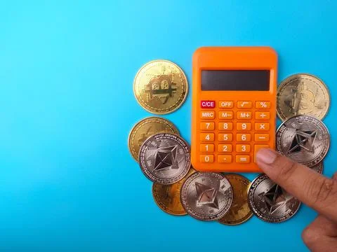 Someone is calculating using a calculator with digital coins Stock Photos