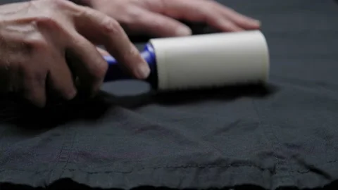 Someone is cleaning clothes with a cleaning roller, hands of a man close-up with Stock Footage 130396733