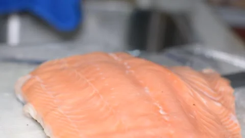 Someone is cutting salmon fillets.  close-up on hands, selective focus. Vidéo 150704363