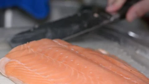 Someone is cutting salmon fillets.  close-up on hands, selective focus. Vidéo 150704367