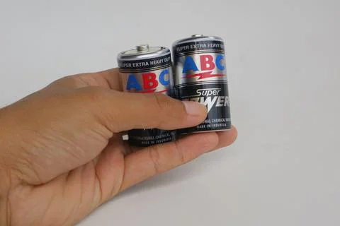 Someone is holding a black battery with the ABC brand Stock Photos