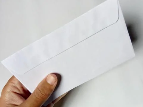 Someone holding a white envelope, in the background. Stock-Fotos
