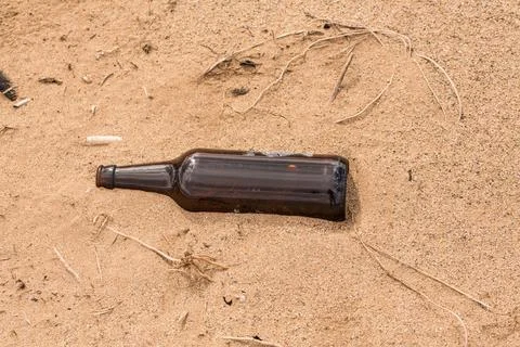 Someone left an empty bottle on the sand instead of recycled it Stock Photos