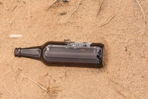 Someone left an empty bottle on the sand instead of recycled it Stock Photos