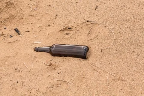 Someone left an empty bottle on the sand instead of recycled it Stock Photos
