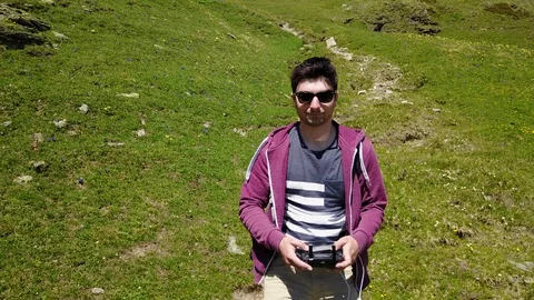 Someone piloting a drone while running on a meadow in the mountains Stock Footage 128948585