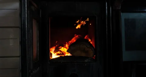 Someone placing a log in the fire, in a wood-burning stove. Stock Footage 211164730