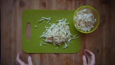 Someone pouring slices of white cabbage from a green cutting board. Stock Footage 104727192
