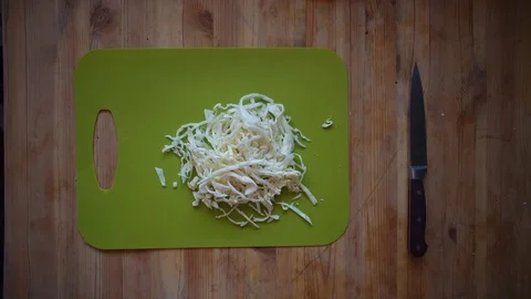 Someone pouring slices of white cabbage from a green cutting board. Stock Footage 104760205