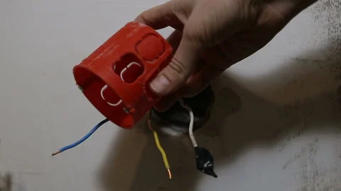 Someone shows a red plastic wall plate against the background of a wall and copp Stock Footage 130927909