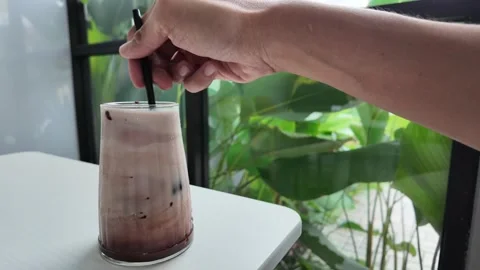 Someone is stirring a cup of cold milk chocolate drinks with a plastic straw Vídeos de archivo 291687841