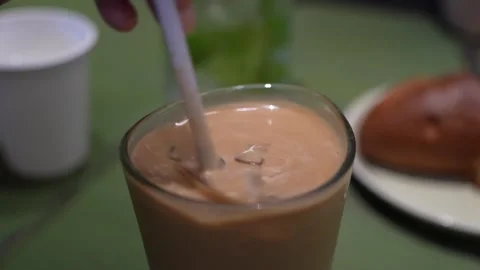 Someone stirring an iced milk coffee by a plastic straw before drinking. Stock Footage 336153889