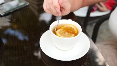 Someone stirs sugar with lemon in mug with green tea. 4k, slow motion. Stock Footage 79372497