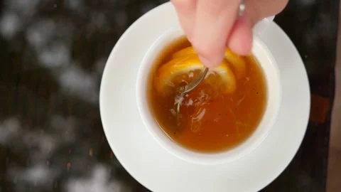 Someone stirs sugar with lemon in mug with green tea. 4k, slow motion. Stock Footage