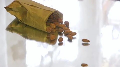 Someone throws a paper bag on the table with almonds, almonds disintegrates Stock Footage 67719386