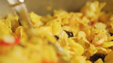 Someone try to mixing a caramel cornflakes with currant, cherry and cashew nuts. Video stock 143635374