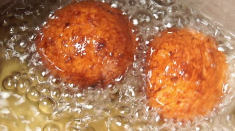 Someone turns the cheese donuts in hot oil using a spoon full of holes Stock Footage 68094208