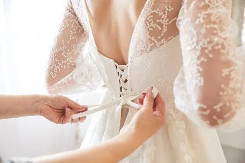 Someone is tying a bow on the back of the bride Stock Photos
