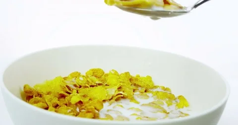 Someone use the spoon for eat cereal corn flakes in a bowl with milk on white Stock Footage 79218984