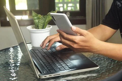 Someone is using mobile banking and a laptop Stock Photos