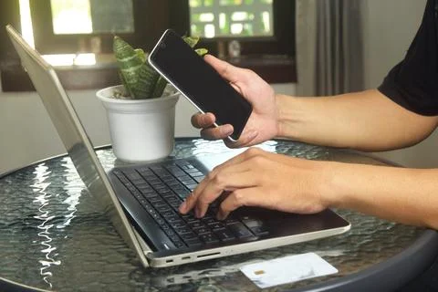 Someone is using mobile banking and a laptop Stock Photos