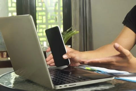 Someone is using mobile banking and a laptop Stock Photos