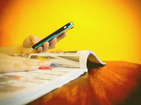 Someone is using telephone while reading a book catalogue to order something Stock Photos