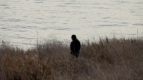 Someone walking down hill towards the water Stock Footage 83137150