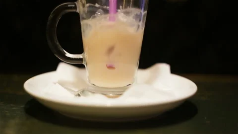 Someone was blowing bubbles with a plastic straw in a coffee, latte in a glass b Stock Footage 99508193