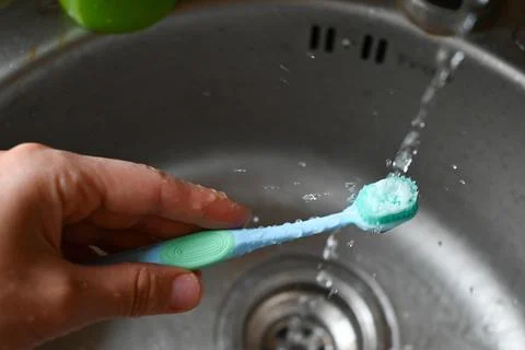 Someone is washing a toothbrush with a toothpaste on it Stock Photos