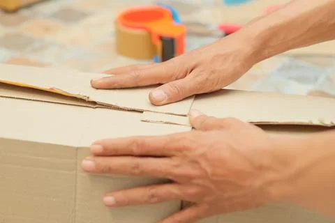 Someone is wrapping a package using cardboard, bubble wrap, and duct tape. .. Stock Photos