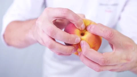 Someone's breaking a peach in half in slow motion. Stock Footage 130853032