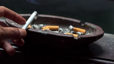 Someone's hand is putting a cigarette in the ashtray Stock Footage 205445535