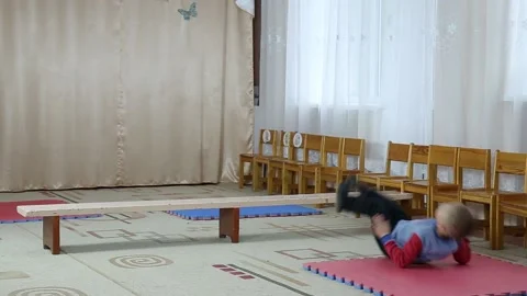 Somersaults and jumping through the bench in the performance of a small athlete Video stock 109404617