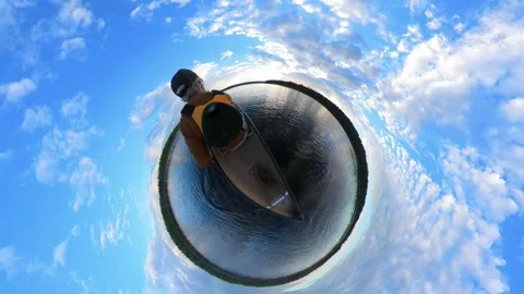 A somewhat goofy 360 degree tiny planet few of a man paddling a canoe on a lake Stock Footage 276975091