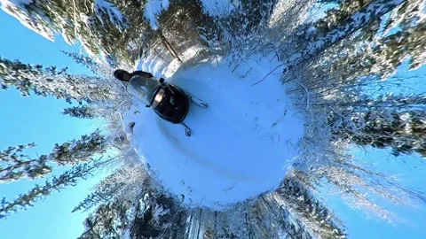 Somewhat goofy looking 360-degree tiny planet clip of a person on a snow machine Stock Footage 249274445