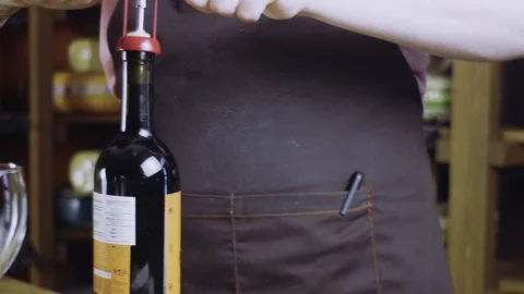 Sommelier opens a bottle of red wine. Two glasses on the table. Shop cheese and Video stock 89163216
