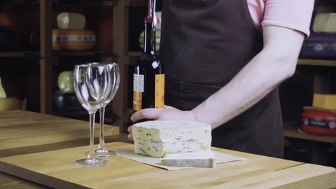 Sommelier opens red wine. On the table is blue cheese. 4k Stock-Footage 89091195