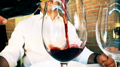Sommelier pouring red wine into diner's glass in slow-motion Stock Footage 92233820