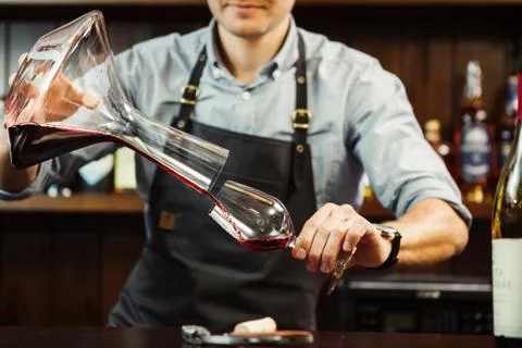 Sommelier pouring wine into glass from mixing bowl. Male waiter Stock Photos