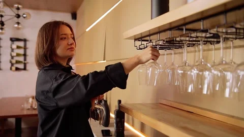 Sommelier preparing for wine tasting event selecting stemware from rack Stock Footage 332231315