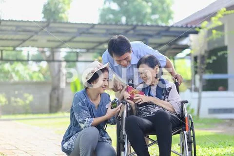Son and daughter in law gift elderly mother in backyard Stock Photos