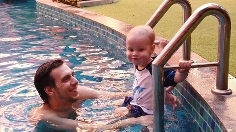 Son and father in the pool, slow motion. in the water playing reflections shinin Stock Footage 104699626