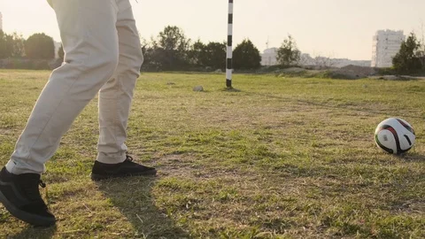 Son and father run down the football field and kick the ball on sunset slow Stock Footage 111431753