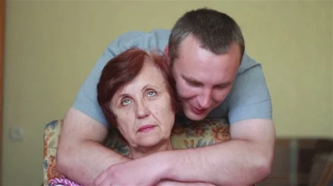 Son approaches and gently hugging elderly mother Stock Footage 64894598