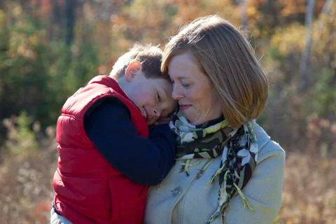 Son is comfortable being held by mom outside Stock Photos