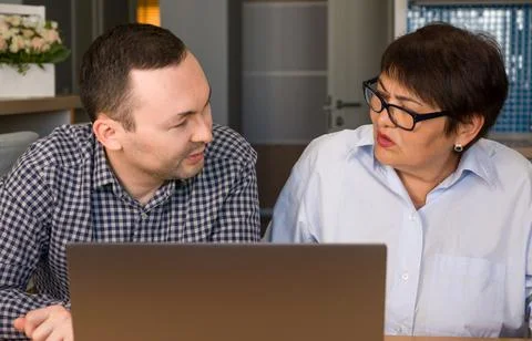 Son explaining mother how to use apps on computer. Stock Photos