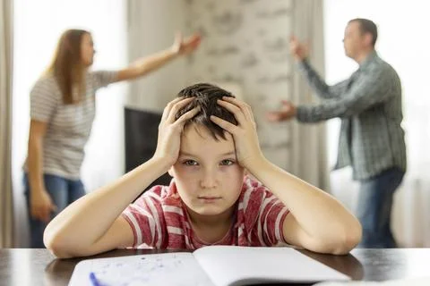 A son feels frustrated while his parents fight in the background Stock Photos