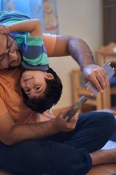 Son has fun on top of his father while assembling furniture. Assembling furni 스톡 사진