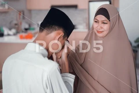 Son kissing her mother hand apologize in eid mubarak Stock Photos